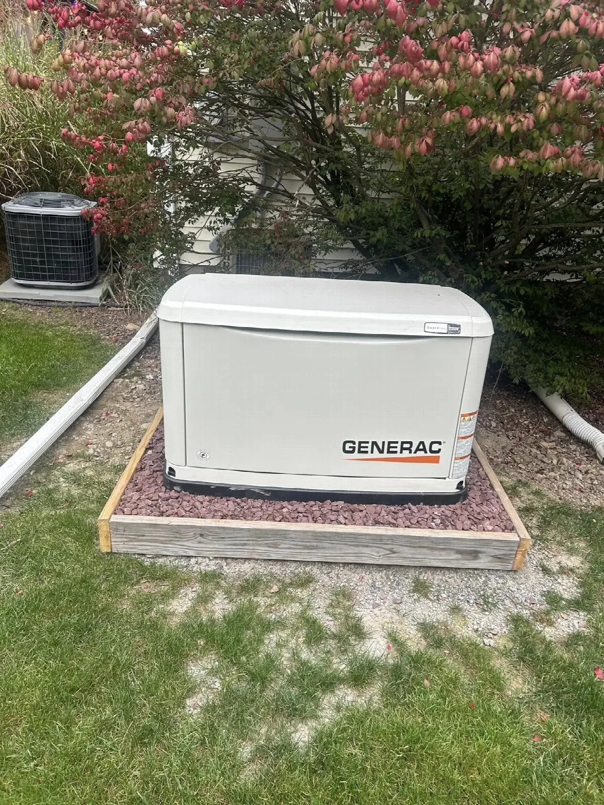 Generac Guardian standby generator installed beside landscaped bushes